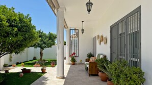 A covered outdoor area with potted plants, a wooden bench, and a hanging light fixture. - Villa Victoria - Ole Solutions (Puerto de Santa María)