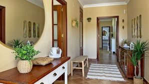 A hallway with a wooden bench, a mirror, and decorative wall art. - Villa Victoria - Ole Solutions (Puerto de Santa María)