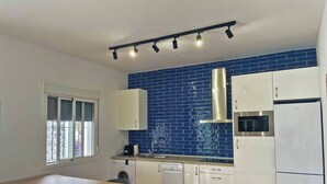 Una cocina moderna con armarios blancos, un salpicadero de azulejos azules, horno empotrado y lavavajillas.