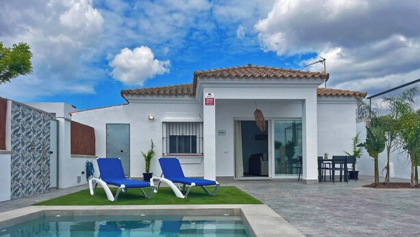 Una casa moderna con piscina, dos sillones azules y un área de patio.