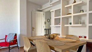 A dining area with a wooden table, chairs, and shelves with decorative items. - Apartamento La Paquera - Ole Solutions (Jerez de la Frontera)