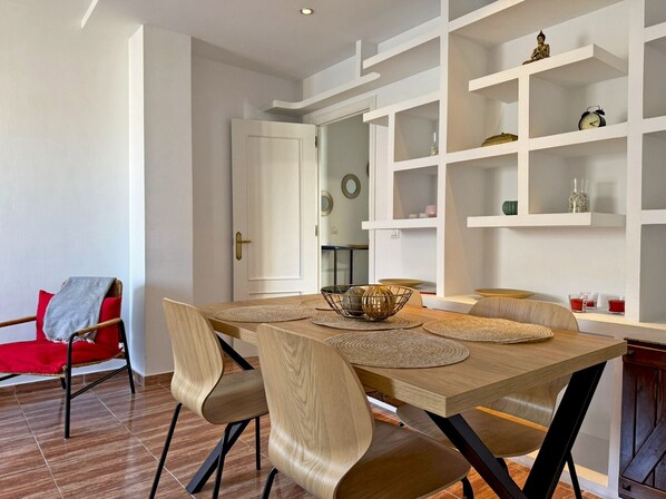 A dining area with a wooden table, chairs, and shelves with decorative items.