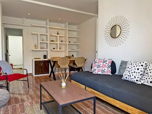 Una sala de estar con un sofá, una mesa de centro y un comedor con sillas y estanterías.