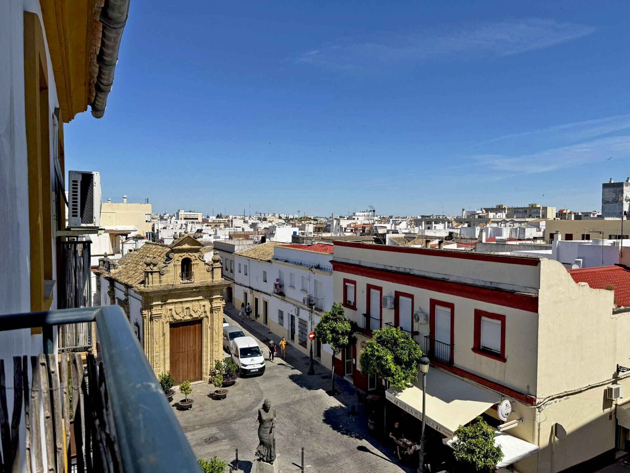 A street view with buildings, a statue, and a clear blue sky.
