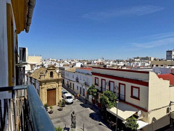 Vista de una calle con edificios, una estatua y un cielo azul despejado.