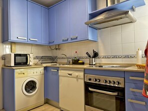 A compact kitchen with blue cabinets, a microwave, a dishwasher, and an oven.
