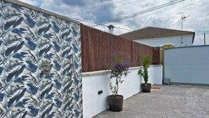 A rooftop patio with a patterned wall, a wooden fence, and two potted plants. - Apartamento Klandestina - Ole Solutions (Conil de la Frontera)