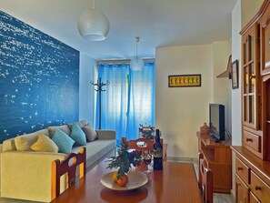 Relax in this stylish living room with a comfortable sofa, dining table, and TV.