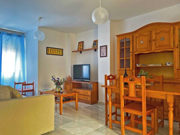 Relax in this inviting living room with a TV, coffee table, and dining area.