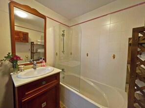 Bathroom features a sink, mirror, and glass-enclosed shower area.