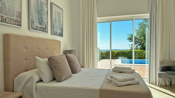 A bedroom with a large bed, a view of a swimming pool, and a cityscape view. - Villa Los Olivos - Ole Solutions (Arcos de la Frontera)