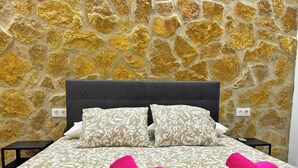 A bed with a patterned bedspread, two pillows, and two rolled towels.