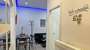 A modern interior with a dining area, a black sofa, and a wall with a motivational quote.