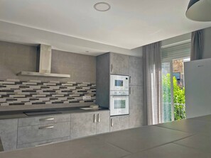 A modern kitchen with grey cabinetry, a patterned backsplash, and a built-in oven.