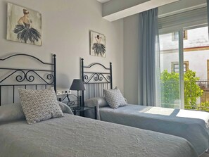 Une chambre d’hôtel avec deux lits, une table de chevet, une lampe et des œuvres d’art accrochées aux murs.