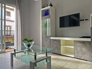 Eine moderne Küche mit Esstisch aus Glas, einem integrierten Fernseher und einem Balkon mit Stadtblick.