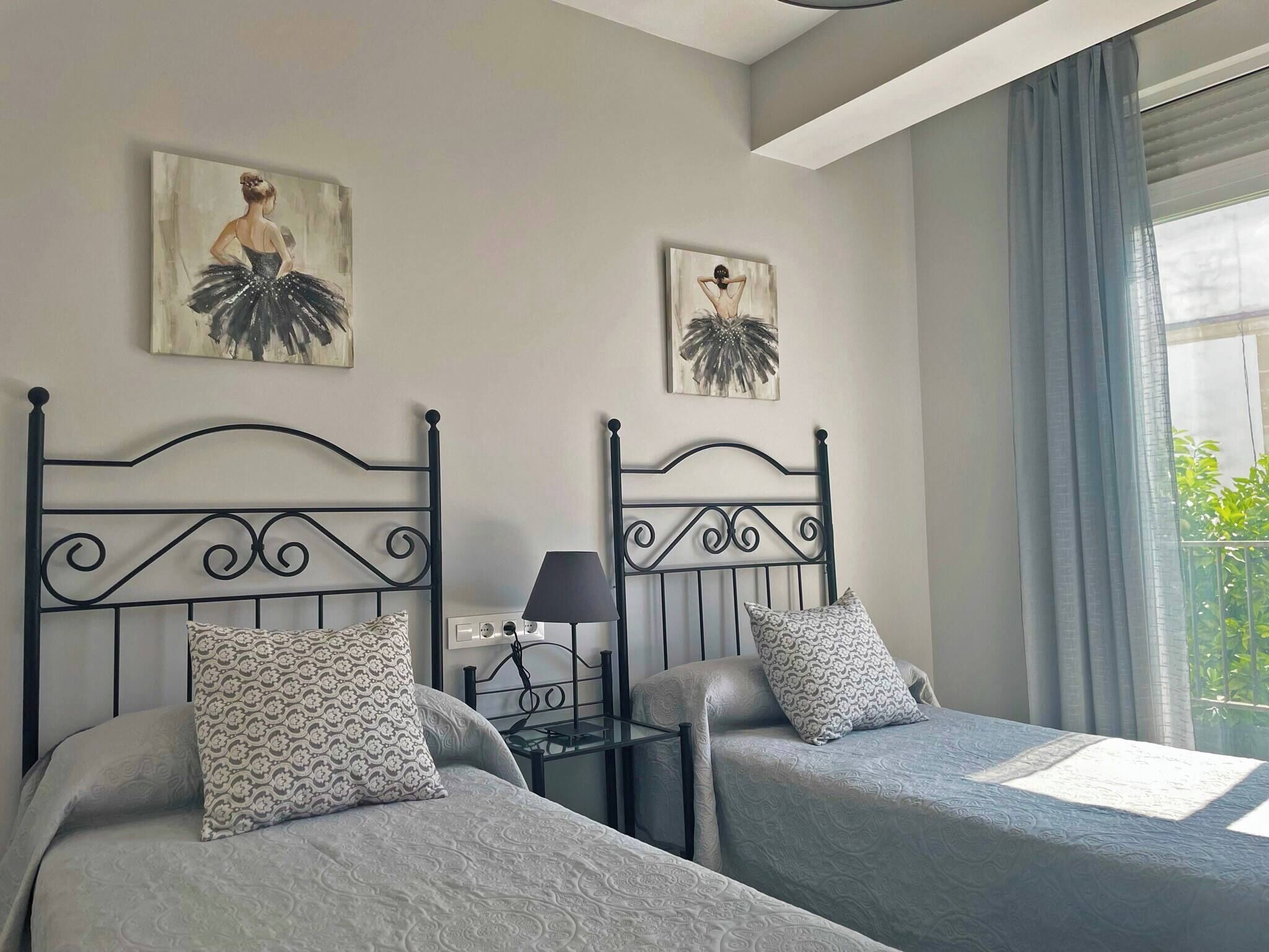 Una habitación de hotel con dos camas, una mesita de noche, una lámpara y obras de arte en las paredes.