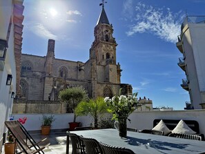 A rooftop terrace with a table, chairs, and potted plants.