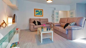 Uma sala de estar moderna com dois sofás, uma mesa de centro e uma luminária pendente.