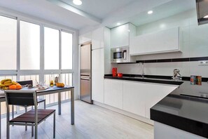 Eine moderne Küche mit weißen Schränken, einer schwarzen Arbeitsplatte und einem Edelstahl-Kühlschrank.