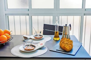 Ein Esstisch mit Orangen, einer Kaffeekanne, einer Ölflasche und einem Croissant.