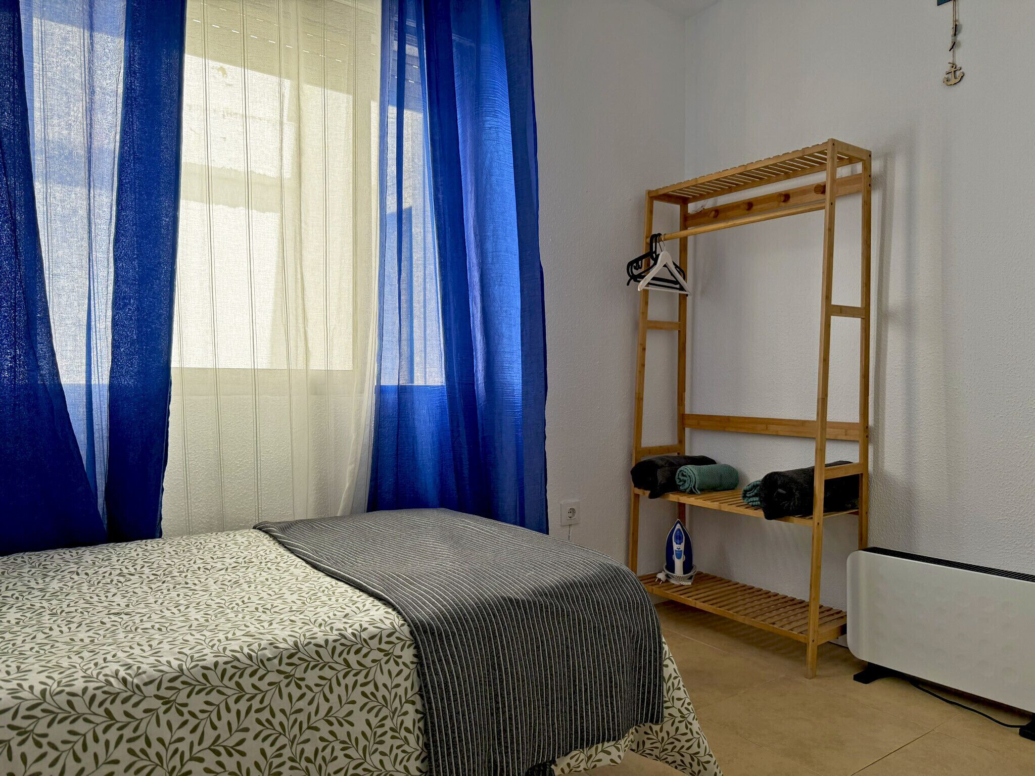 A bedroom with a bed, a wooden shelf unit, and a radiator.