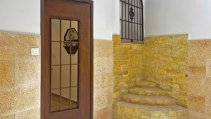 Una esquina con una puerta de madera, un muro de piedra y una reja de metal.