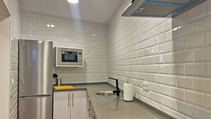 Una cocina moderna con azulejos tipo metro blancos, electrodomésticos de acero inoxidable y un microondas integrado.