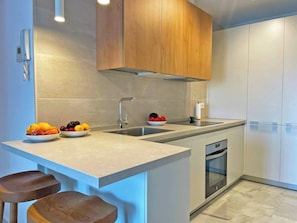 A modern kitchen with a built-in island, stainless steel appliances, and wooden cabinetry. - Apartamento El Carmen - Ole Solutions (Jerez de la Frontera)