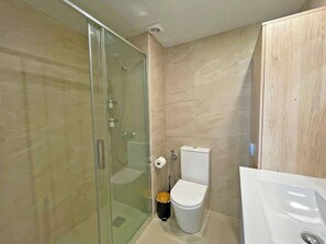 Un baño moderno con ducha acristalada, inodoro y lavabo.