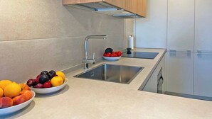 A modern kitchen with two sinks, a stainless steel faucet, and wooden cabinets. - Apartamento El Carmen - Ole Solutions (Jerez de la Frontera)