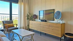 Un salon moderne avec un canapé, une table basse, un téléviseur et une plante.