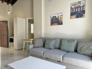A modern living room with a grey sofa, a white coffee table, and a wooden door.