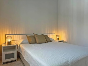 Quarto com uma cama, duas mesas de cabeceira e duas luminárias.