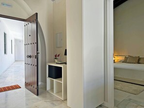 A hotel room with a bed, a desk with a lamp, and a wardrobe.