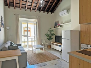 Ein gemütlicher Wohnbereich mit Sofa, Esstisch, Fernseher und Küchenzeile inklusive Kühlschrank und Spüle.