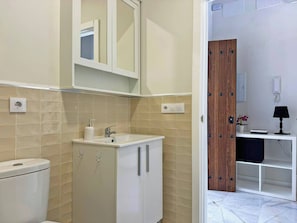 Ein modernes Badezimmer mit Waschbecken, Spiegel und Schrank. Eine Toilette ist links im Bild zu sehen.