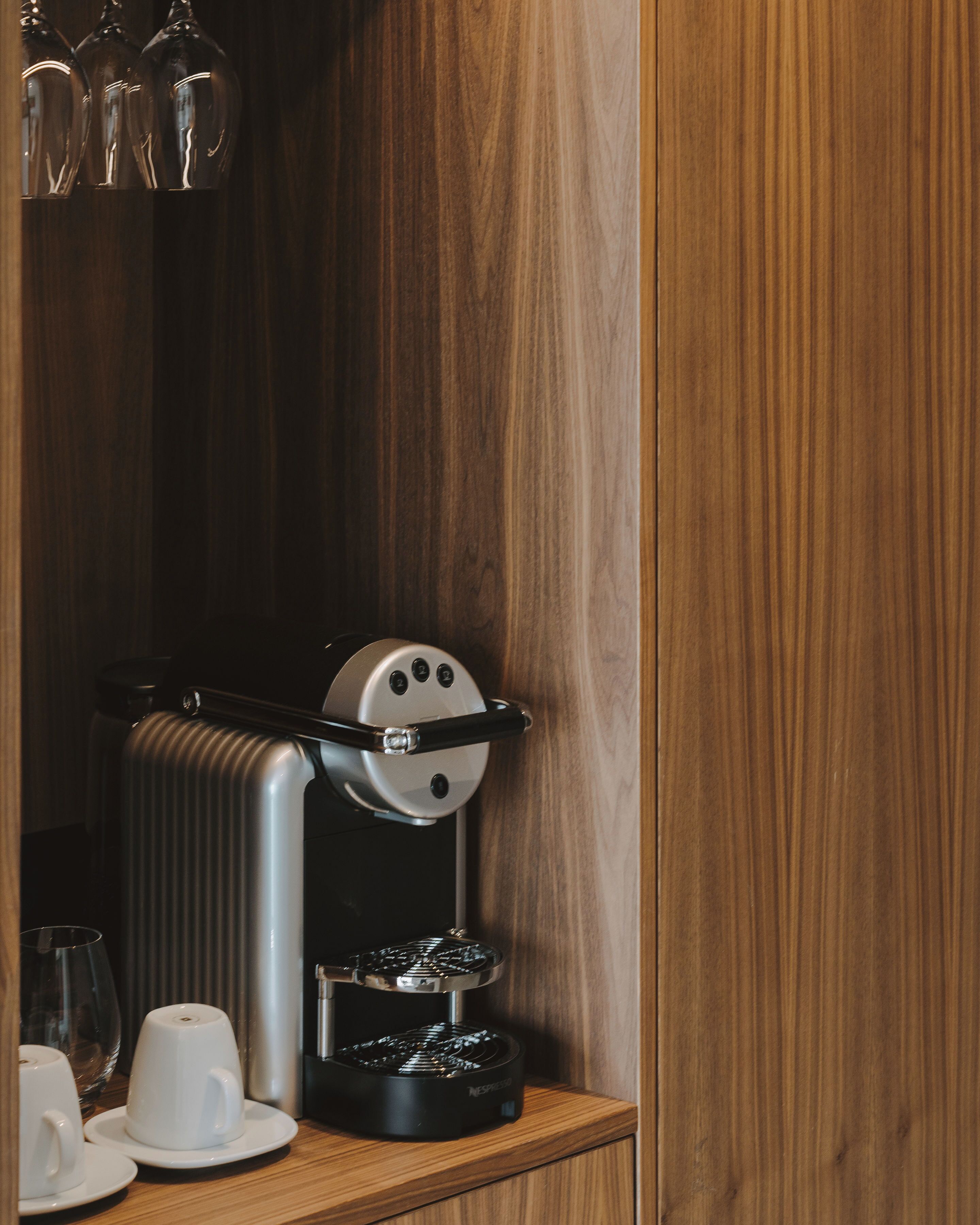A coffee machine with a control panel and a drip tray on a wooden counter.