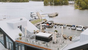 A modern building with a glass facade and a rooftop terrace with outdoor seating. - Season Hotel (Ekerö)