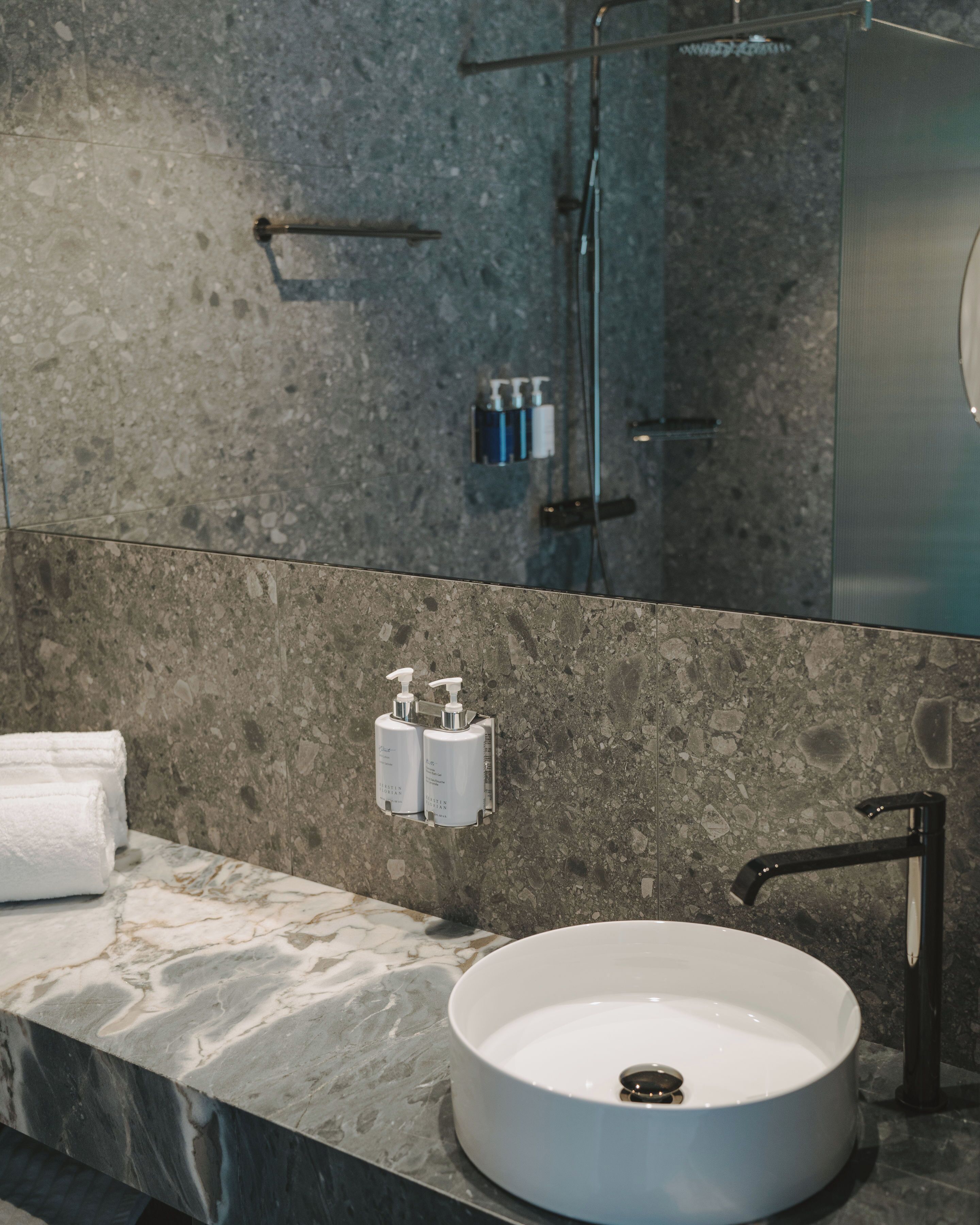 A bathroom with a marble countertop, a white sink, and a large mirror.