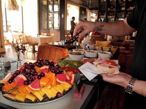 A buffet table with a variety of fruits and a person serving food.
