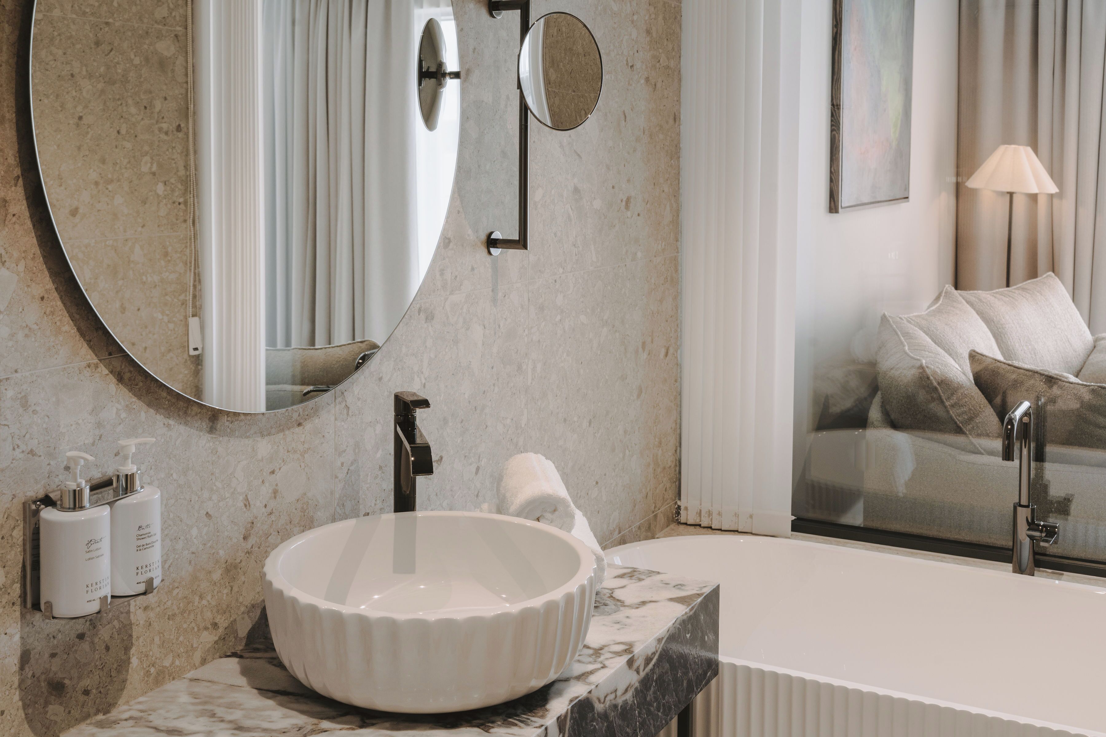 Un baño con un lavamanos redondo blanco, un espejo y un perchero para toallas.