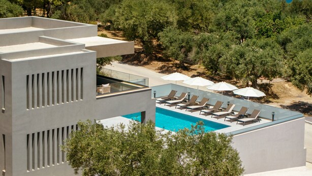 A modern hotel with a rooftop pool, lounge chairs, and umbrellas. - Villa Frantzeska (Zakynthos)