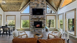 A spacious living room with a stone fireplace, large windows, and leather seating.
