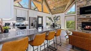 A modern kitchen with a large island, bar stools, and a fireplace.