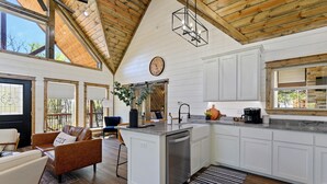 A spacious kitchen with white cabinetry, a central island with a dishwasher, and a wooden ceiling.