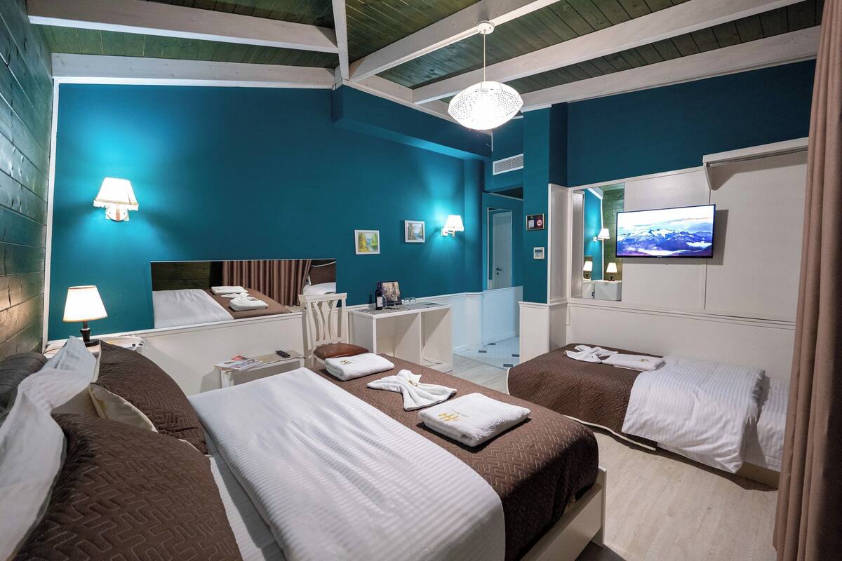 A hotel room with two beds, a desk, a TV, and a bathroom visible through an open door.