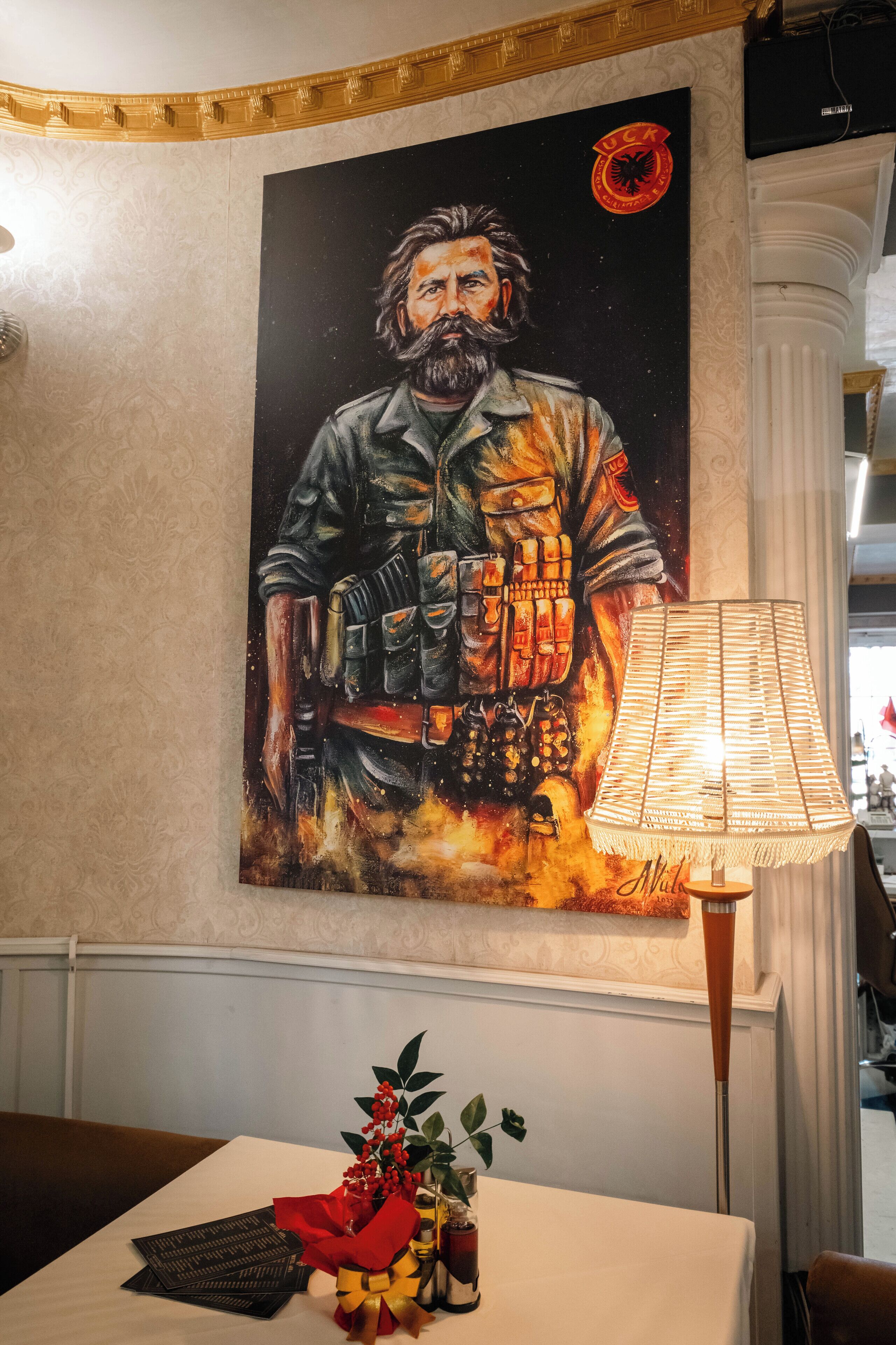 Een eetgedeelte met een tafel gedekt voor twee personen, een lamp en een aan de muur hangend schilderij.