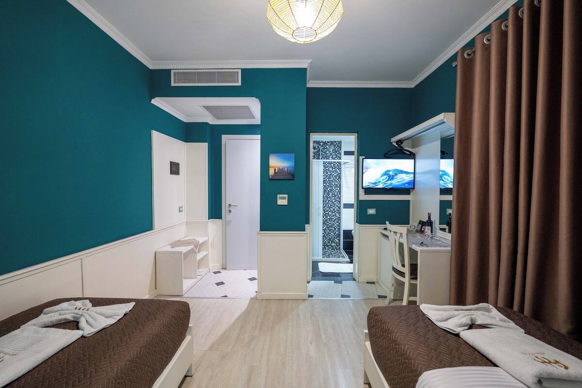 A hotel room with two beds, a TV, a desk, and a bathroom.