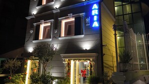 A two-story building with a neon sign reading "ARIA" and a red awning. - Hotel Aria (Tirana)